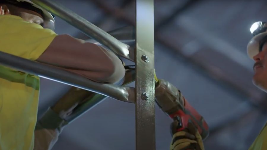 Two Material Handling Installers tighten bolts on pallet rack structural beams